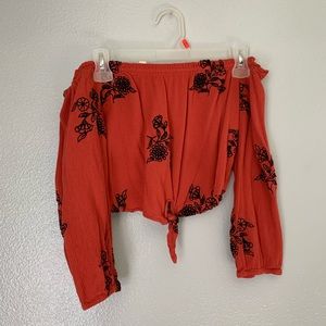 Red long sleeved crop top w black designs.